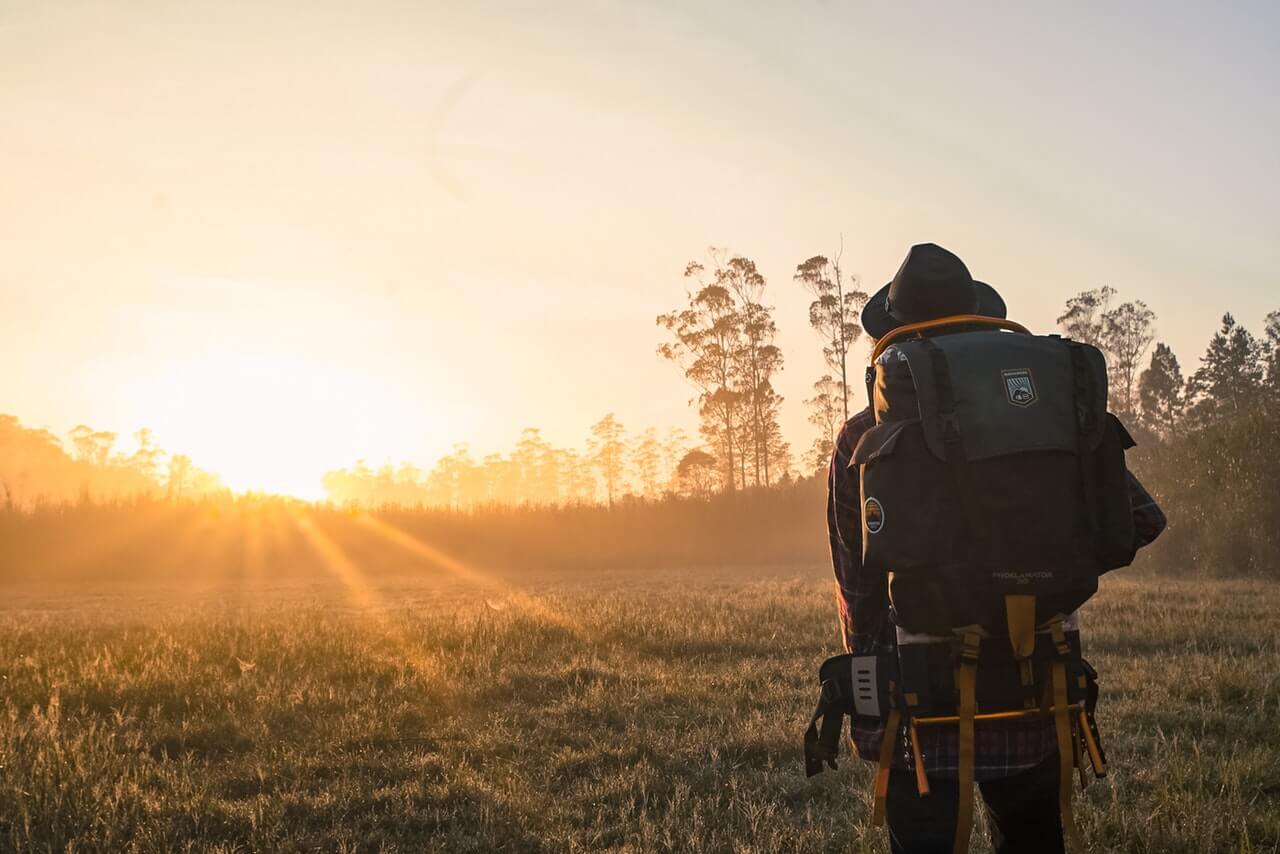Person backpacking in a meadow during golden hour.
