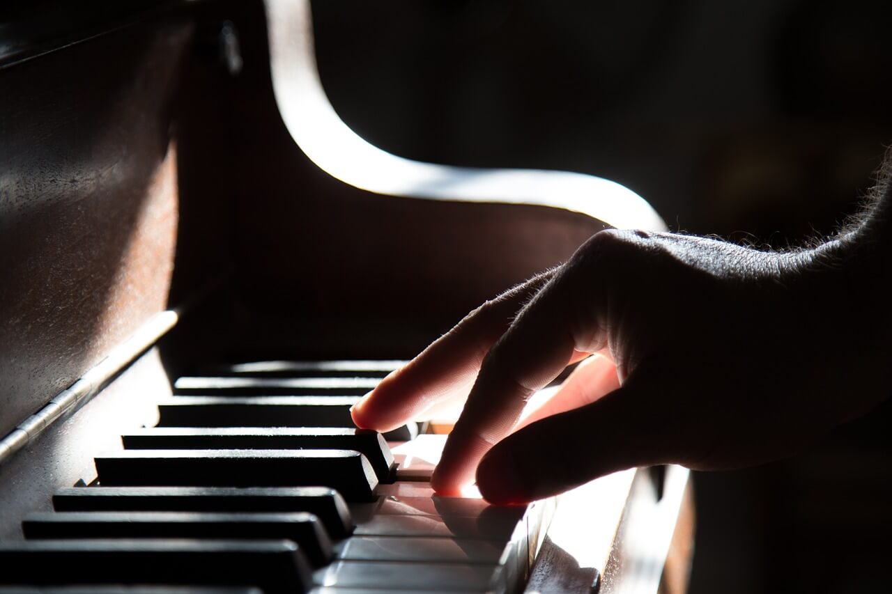 A dramatic, sunlit hand playing the piano.