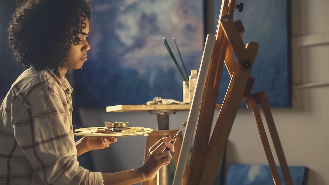 A side profile of a woman working intently on her painting.