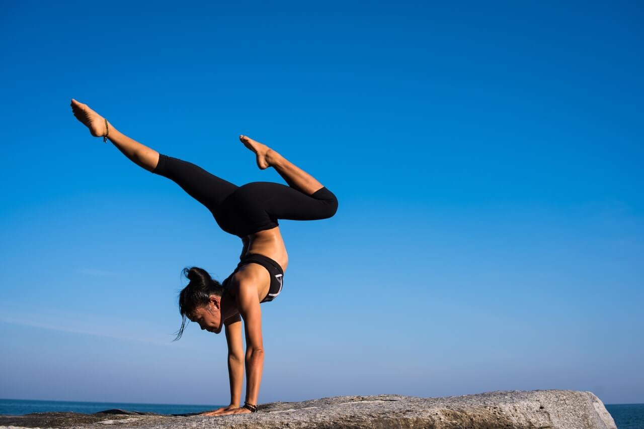 Woman performing inspirational yoga on a rocky outcropping by the sea